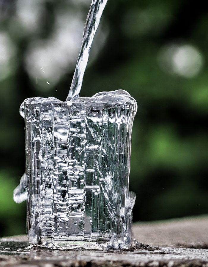 Close-up of water being poured into a glass, creating a dynamic splashing effect.