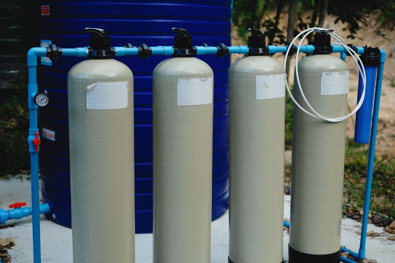 Mastering the First Impression: Your intriguing post title goes here Four beige tanks in an outdoor water treatment setup with blue piping.