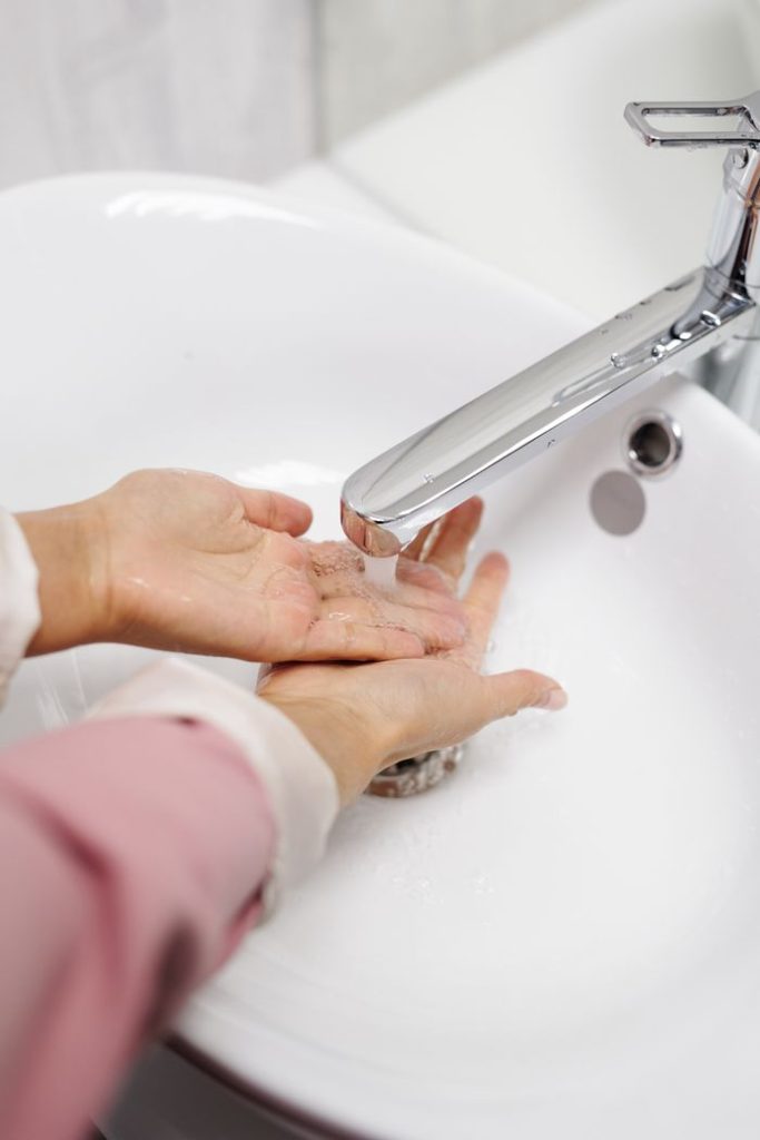 Hands being washed under a faucet with running water to promote hygiene.
